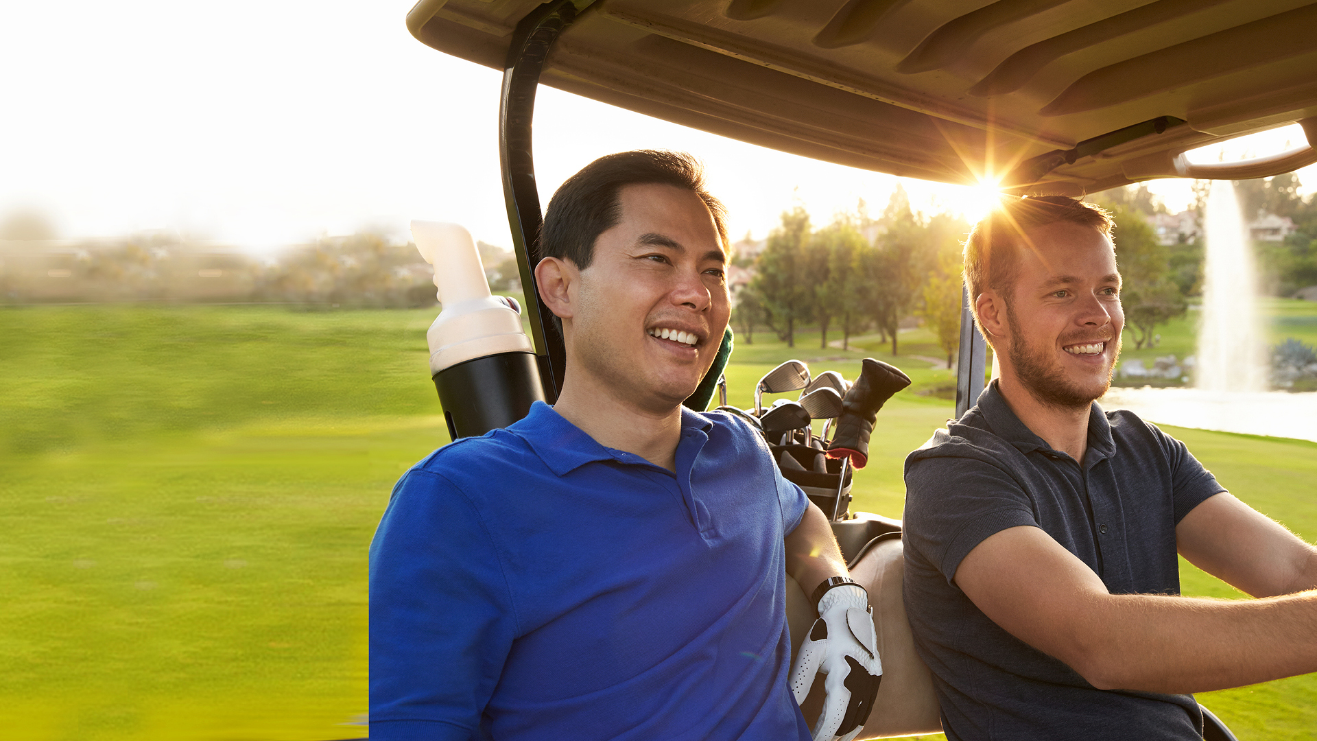 Two friends smiling in a golf cart.