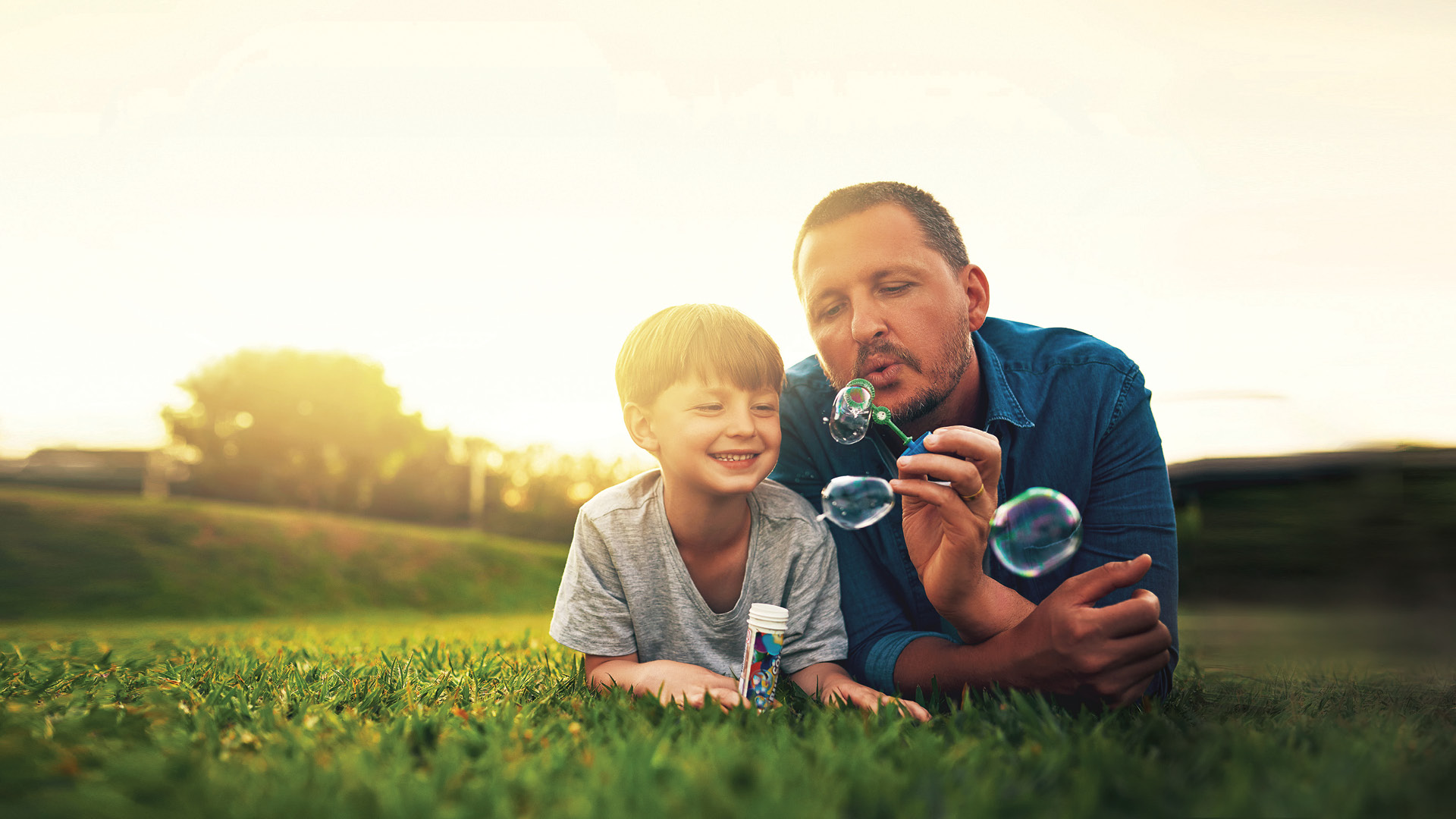 Father and son on hilltop blowing bubbles.