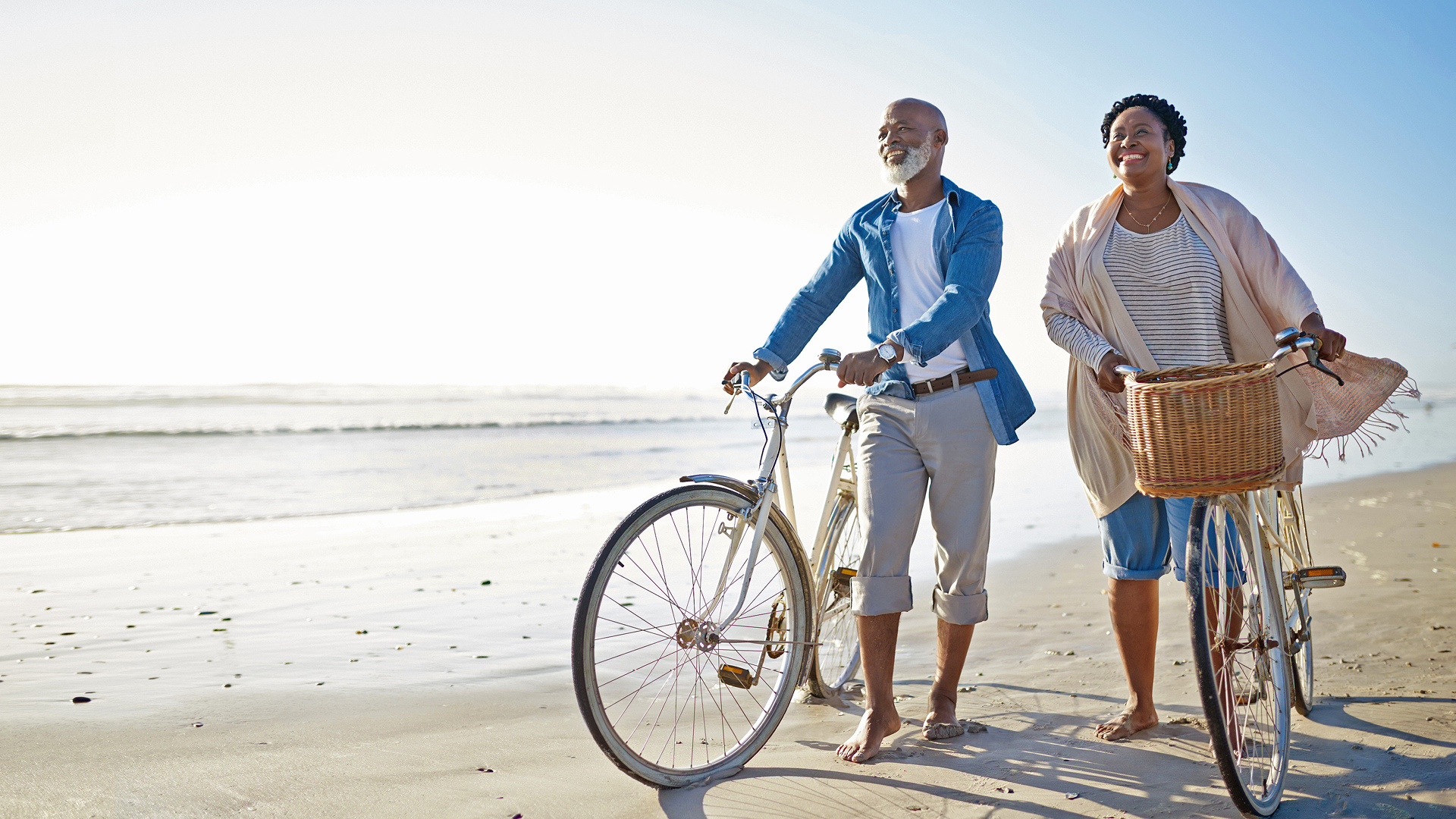 Senior couple waling bikes along a Central Coast beach.