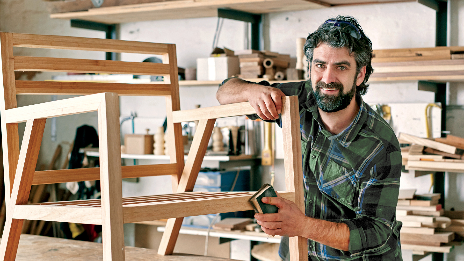 A carpenter in his shop working on a new wooden chair.