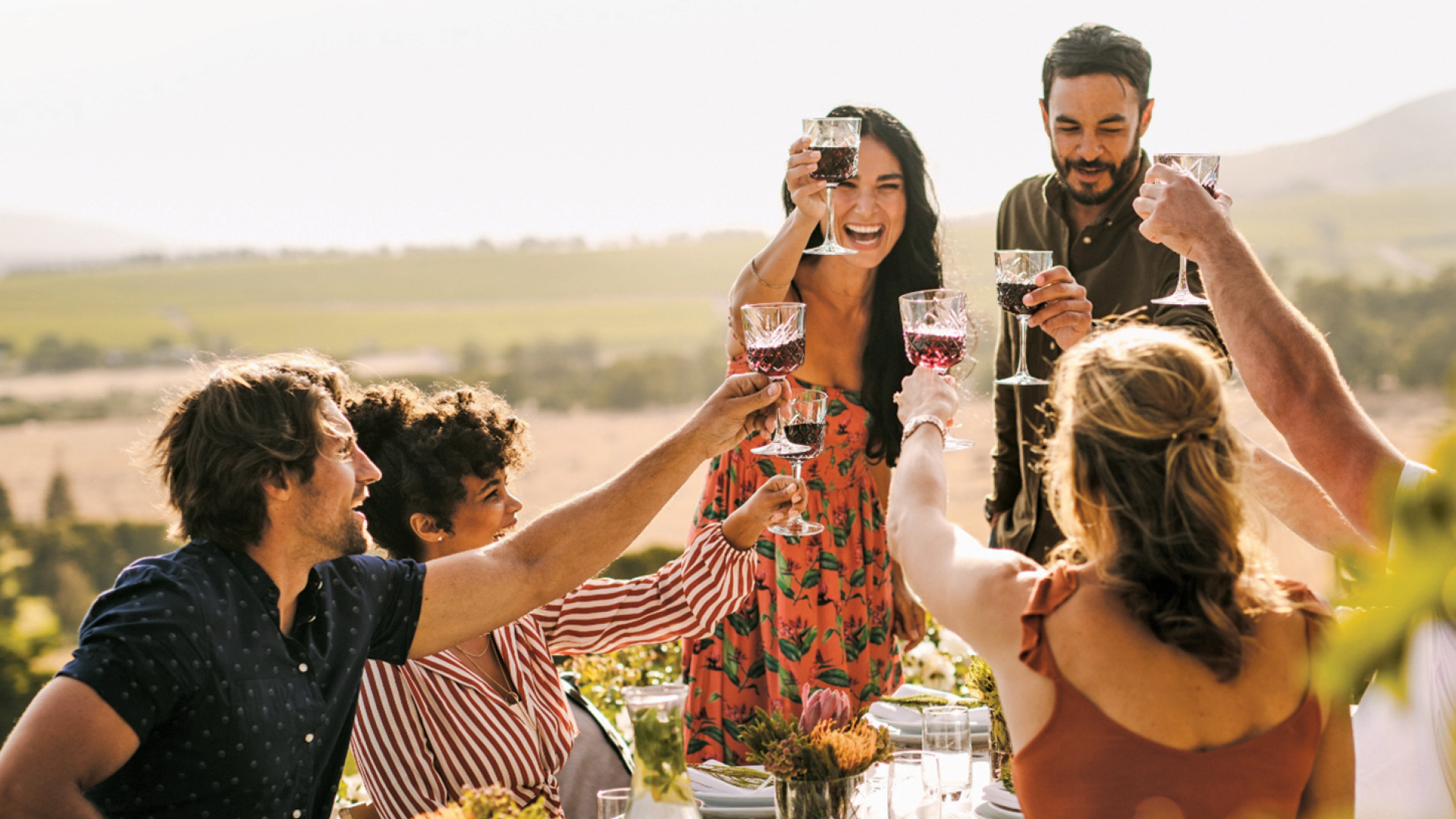 Friends in a vineyard enjoying a meal and toasting the good life on the Central Coast.