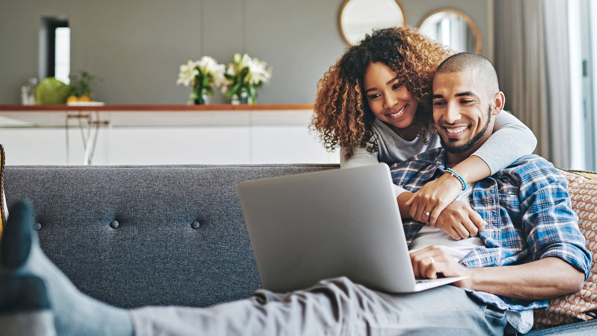 A couple reviews their finances on a laptop from the comfort of home.