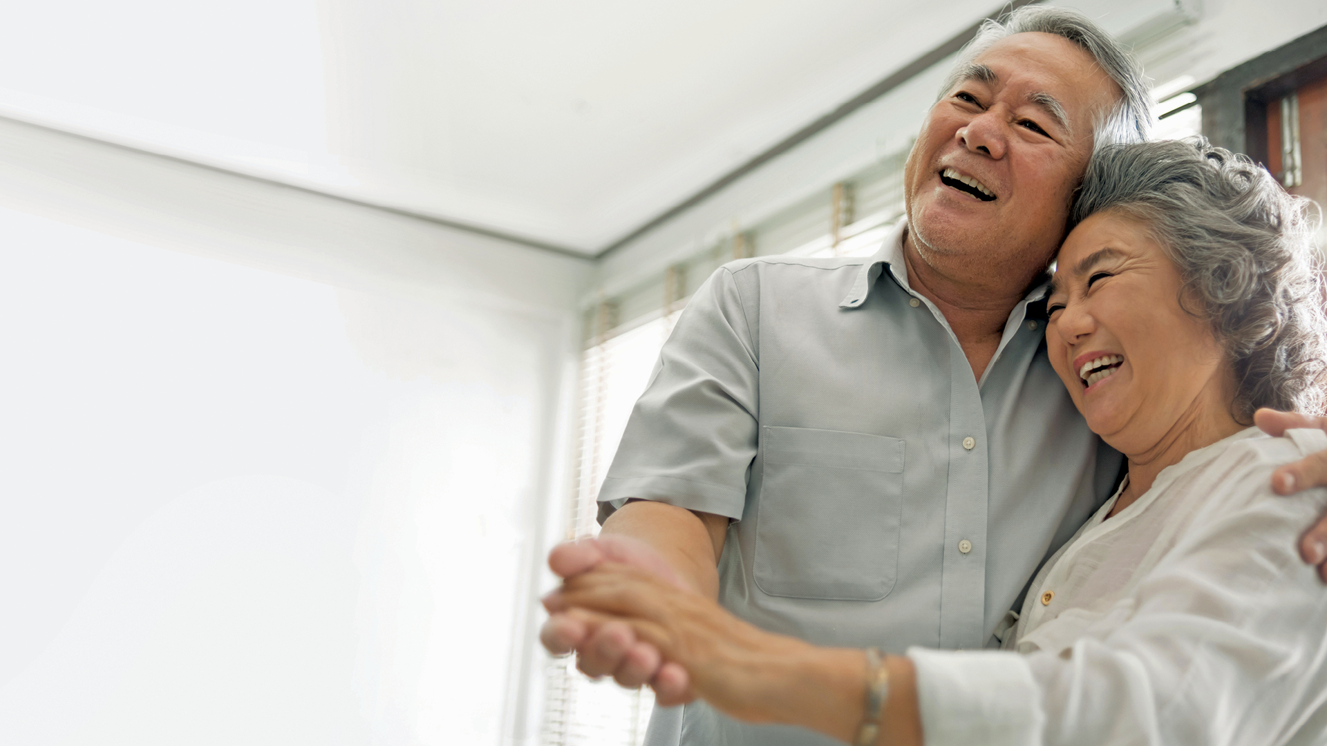 Senior couple dancing with joy after saving money on their home loan.