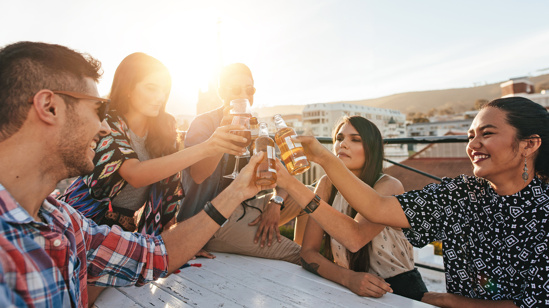 A group of friends make a toast to good times on the Central Coast while at a rooftop restaurant.