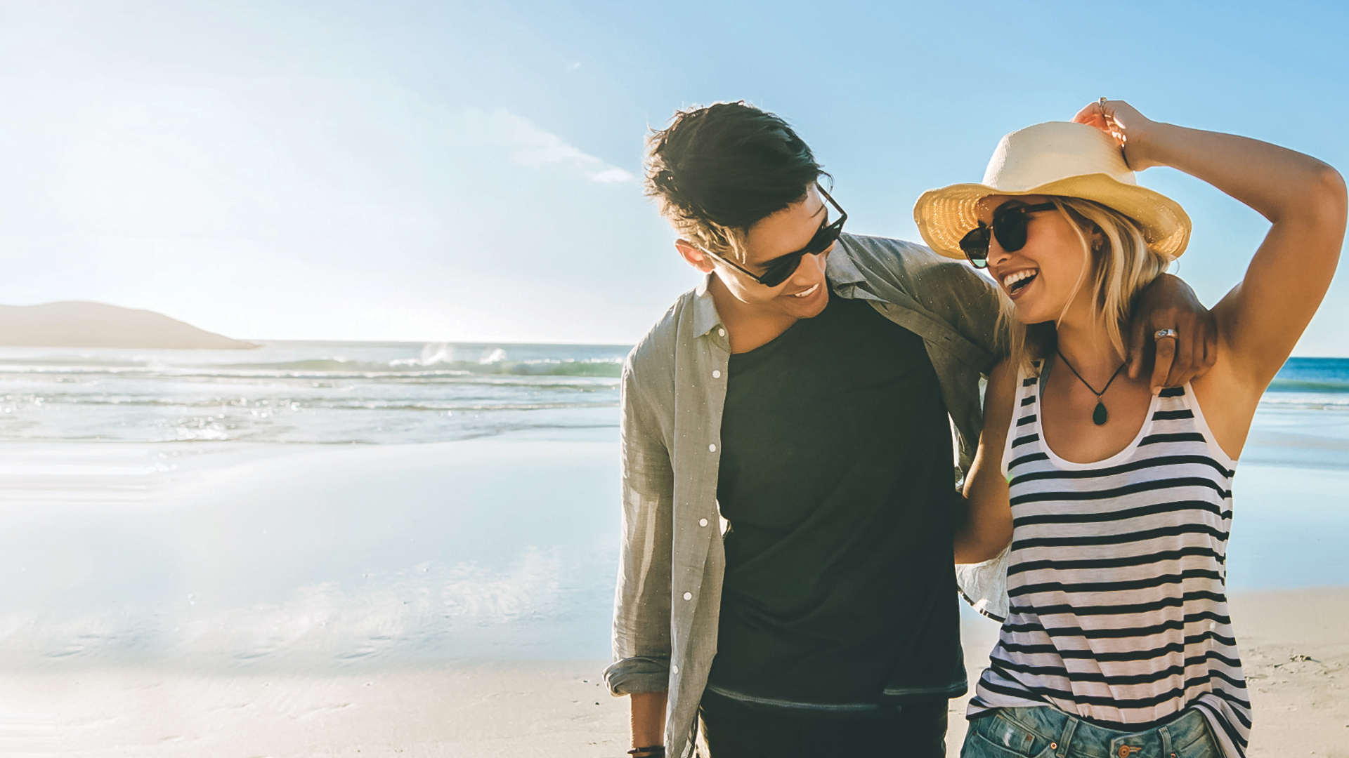 A young couple enjoys walking down a Central Coast beach.