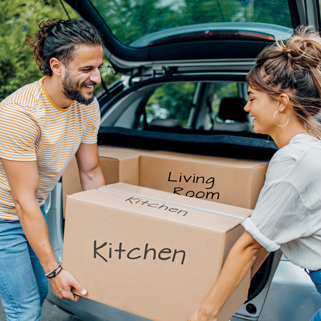 Couple unloads boxes from car as they move into their new home.