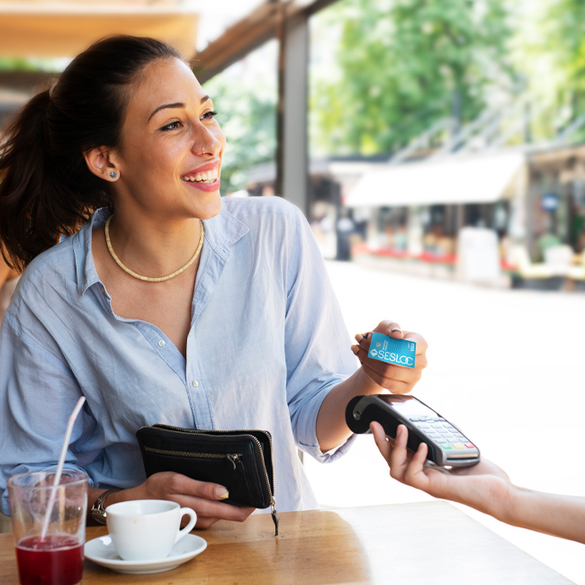 Woman using her SESLOC Rewards card at a local business.